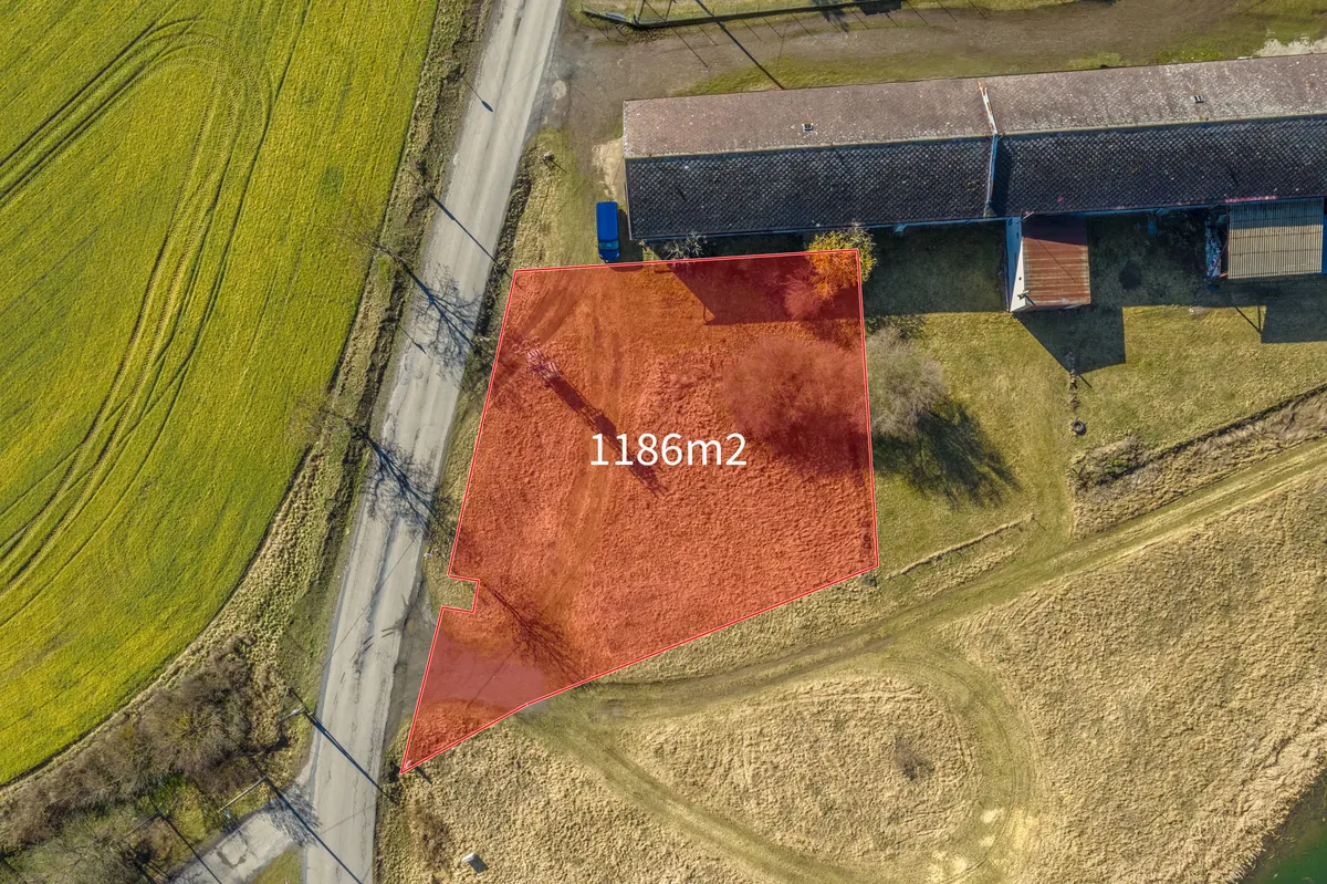 Nabízená parcela 92/3 s orientačně vyznačeným obrysem, vedle komunikace a hospodářské budovy